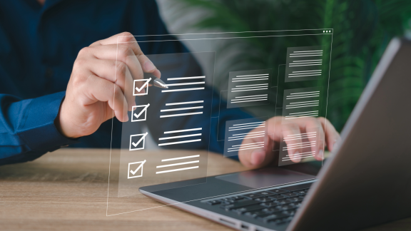 Person arbeitet am Laptop mit digitaler Checkliste und virtuellen Häkchen