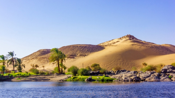 Landschaft in Ägypten mit Palmen, Nil und Wüste im Hintergrund