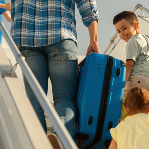 Young couple with luggage at the airport, cheerfully waving—ready for their international move. Bright, busy terminal scene.