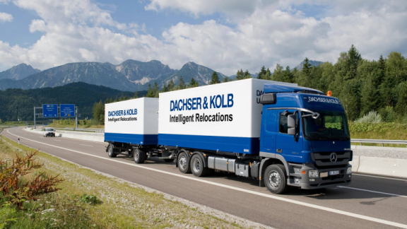 Ein blauer Lkw-Zug von DACHSER & KOLB transportiert Umzugsgut bei einem deutschlandweiten Fernumzug auf der Autobahn.