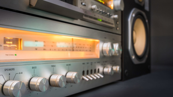 Ein beleuchteter Vintage-HiFi-Verstärker mit silbernen Drehknöpfen und Kippschaltern vor dem geschützten Transport durch DACHSER & KOLB.
