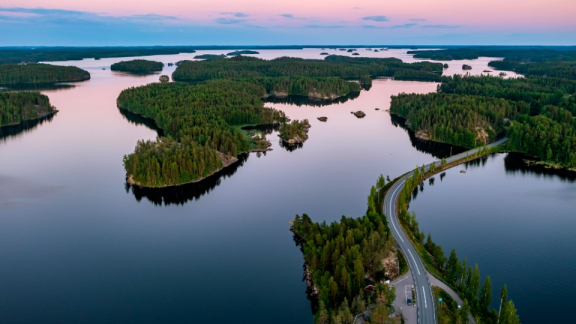 Luftaufnahme von finnischer Seenlandschaft mit Inseln, Wald und Straße über dem Wasser