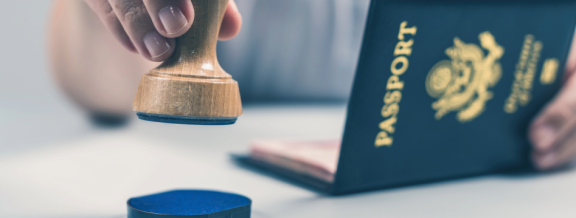 Hand mit Stempel vor Reisepass als Symbol für Einreise und Dokumente bei einem Umzug nach Finnland