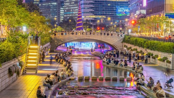 Belebter Cheonggyecheon in Seoul bei Nacht mit Brücke, Lichtern und Spaziergängern
