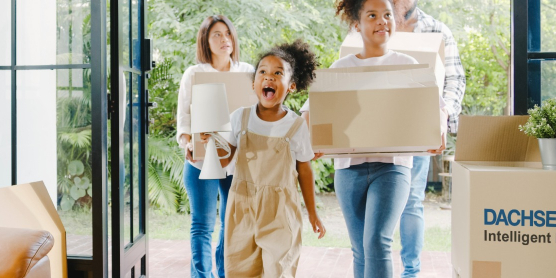 Familie trägt Umzugskartons ins neue Zuhause – Symbolbild für praktische Wohntipps