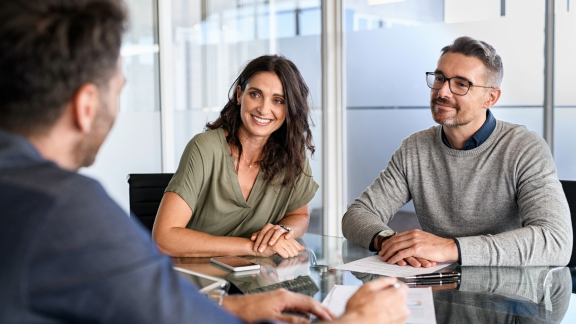 Ein Paar im Beratungsgespräch mit einem Relocation-Spezialisten, symbolisiert den Relocation Service für Privatpersonen.