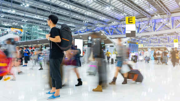 Reisender mit Rucksack im belebten Flughafen vor dem Abflug nach Thailand