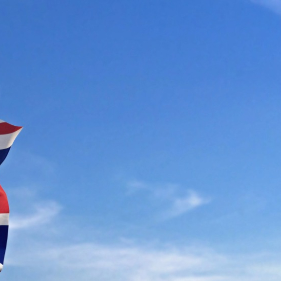 Britische Flagge (Union Jack) an Fahnenmast vor blauem Himmel