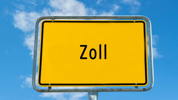 Yellow road sign reading “Zoll” against a blue sky