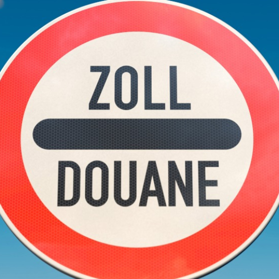 Customs barrier with “Zoll/Douane” sign in front of EU flag, symbol for customs Thailand to Germany.