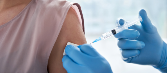 Medizinische Impfung in den Oberarm einer Person mit Spritze und Handschuhen