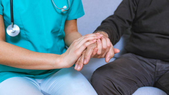 Rumänischer Arzt hält die Hand eines Patienten